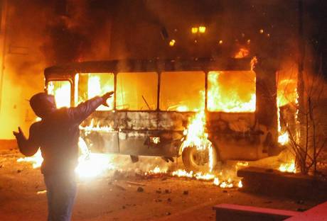 Redazione di Operai Contro, Nonostante l’uso delle armi da parte della polizia, nella notte i dimostranti sono tornati a lanciare molotov e pietre contro gli agenti, I pulmini della polizia bruciati nei giorni scorsi, e prima schierati a difesa del cordone di agenti attaccato dai manifestanti, fanno ora da scudo agli stessi dimostranti, che hanno rinforzato la barriera mettendo in piedi delle barricate improvvisate e per incoraggiarsi battono ritmicamente con mazze e spranghe contro pali della luce e altri oggetti metallici. L’ingresso di un edificio che dà sulla strada teatro degli scontri è stato trasformato dagli insorti in un […]