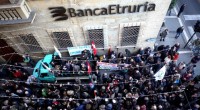 Redazione di O.C. “La casta colpisce ancora. Boschi e Renzi fuori i soldi”, con questo striscione alcuni militanti di centri sociali di Milano hanno denunciato, fuori dalla sede milanese della banca Etruria, tutta la loro avversione contro il decreto salva banche del governo Renzi. Imbrattando, con lanci di vernice le vetrine e i bancomat della banca, gridando slogan contro le banche e il governo, le vere associazioni a delinquere al servizio dei padroni. Il decreto, che di fatto a concesso il salvataggio della banca del padre del ministro Boschi, ha permesso alle banche un ulteriore salvataggio dei loro profitti. […]